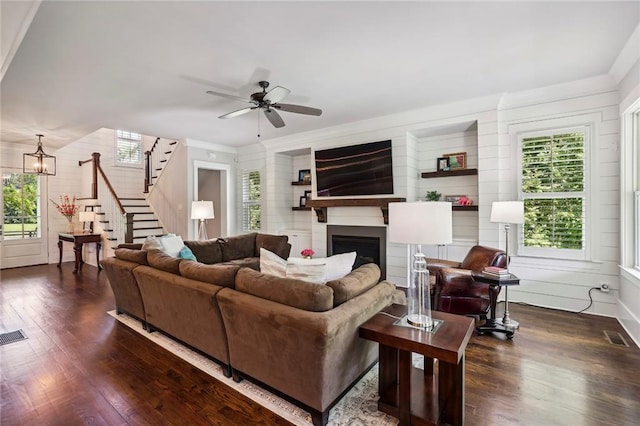 living area featuring wood finished floors, a healthy amount of sunlight, a fireplace, and stairs