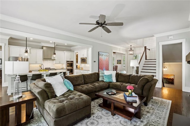 living room with recessed lighting, ceiling fan with notable chandelier, stairs, ornamental molding, and light wood-type flooring