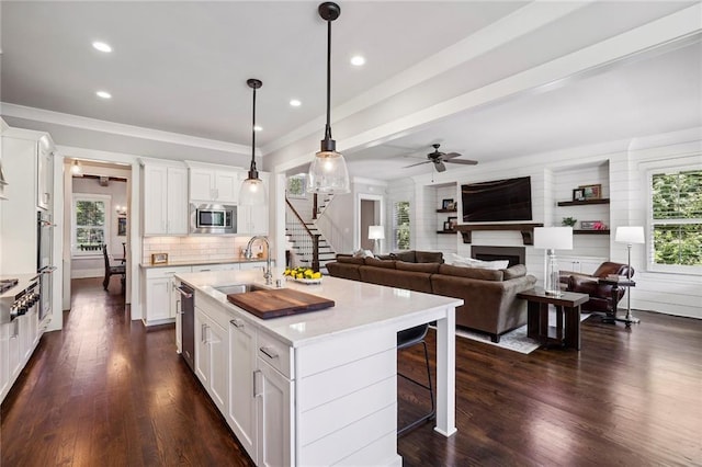 kitchen with a fireplace, a sink, white cabinetry, appliances with stainless steel finishes, and a wealth of natural light