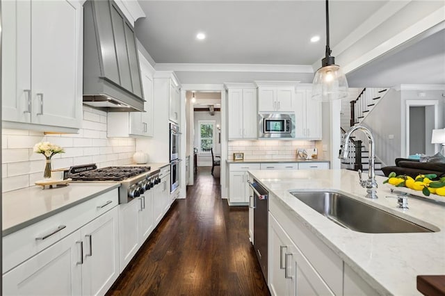 kitchen featuring dark wood-style floors, custom range hood, appliances with stainless steel finishes, light stone countertops, and a sink