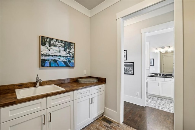 bathroom featuring crown molding, brick floor, vanity, and baseboards