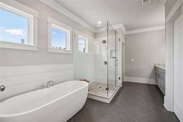 bathroom featuring crown molding, a stall shower, vanity, a freestanding tub, and baseboards