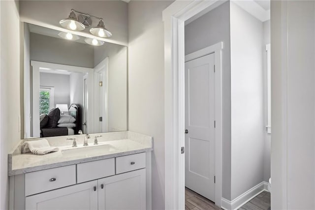 bathroom with connected bathroom, wood finished floors, vanity, and baseboards