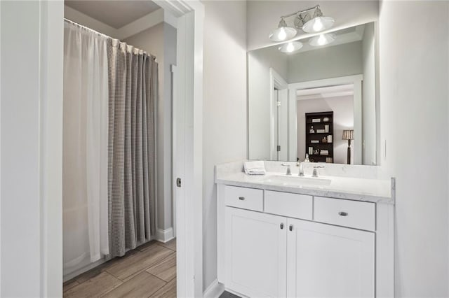 bathroom featuring a shower with curtain, baseboards, wood finished floors, and vanity