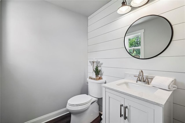 bathroom with toilet, baseboards, wood finished floors, and vanity