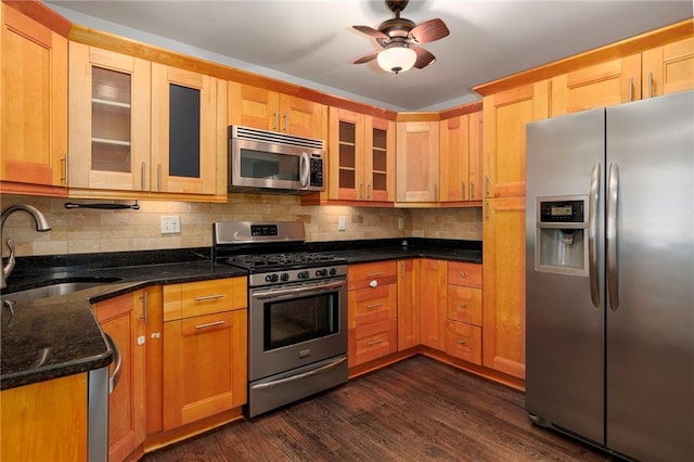 kitchen with backsplash, dark stone counters, sink, dark hardwood / wood-style floors, and stainless steel appliances