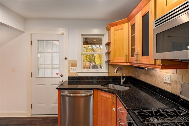 kitchen featuring sink, stainless steel appliances, dark hardwood / wood-style flooring, dark stone counters, and decorative backsplash