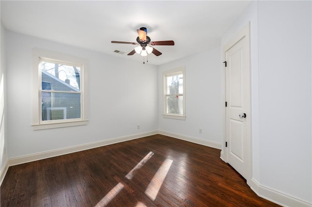 empty room with dark hardwood / wood-style floors, plenty of natural light, and ceiling fan