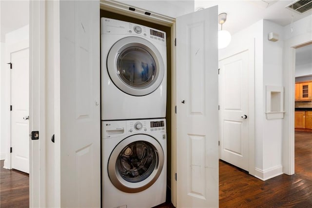 laundry area featuring dark hardwood / wood-style floors and stacked washing maching and dryer