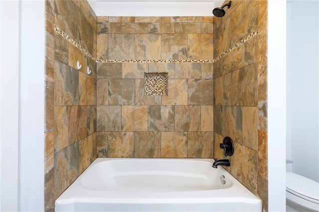 bathroom featuring tiled shower / bath combo and toilet