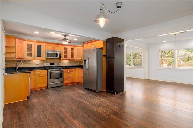 kitchen featuring backsplash, sink, hanging light fixtures, ceiling fan, and appliances with stainless steel finishes