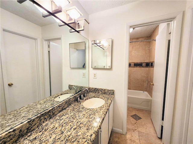 bathroom with a textured ceiling, vanity, tile patterned floors, and tiled shower / bath