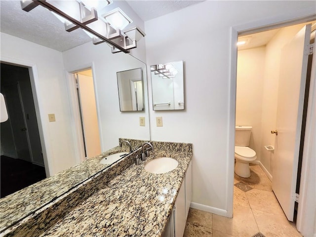 bathroom with vanity, toilet, tile patterned floors, and a textured ceiling