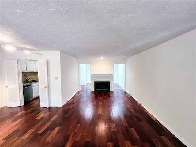 unfurnished living room with a textured ceiling, sink, and wood-type flooring