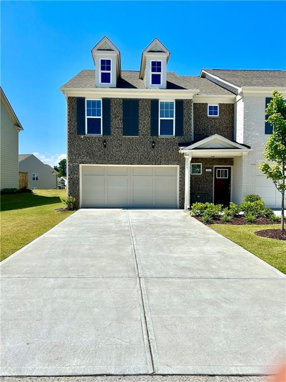 view of front of home featuring an attached garage, concrete driveway, and a front yard