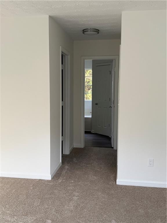 corridor featuring carpet flooring and a textured ceiling