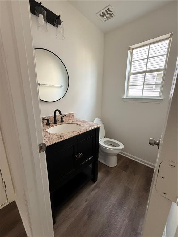 bathroom with wood-type flooring, vanity, and toilet