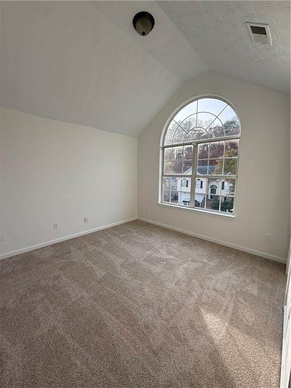 carpeted spare room featuring vaulted ceiling