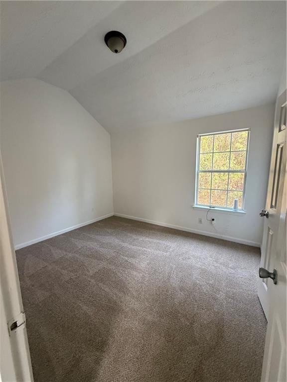 carpeted spare room with lofted ceiling