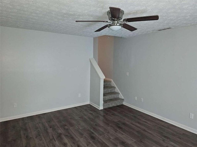 empty room with ceiling fan, dark hardwood / wood-style floors, and a textured ceiling