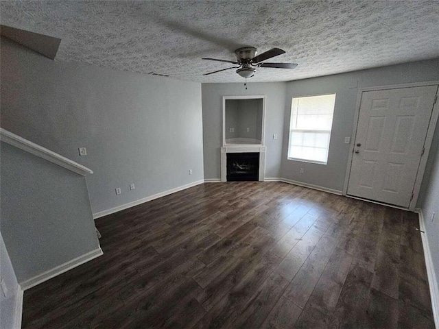 unfurnished living room featuring ceiling fan, a textured ceiling, and dark wood-type flooring