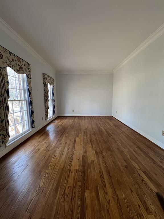 spare room with dark wood-style floors, ornamental molding, and baseboards