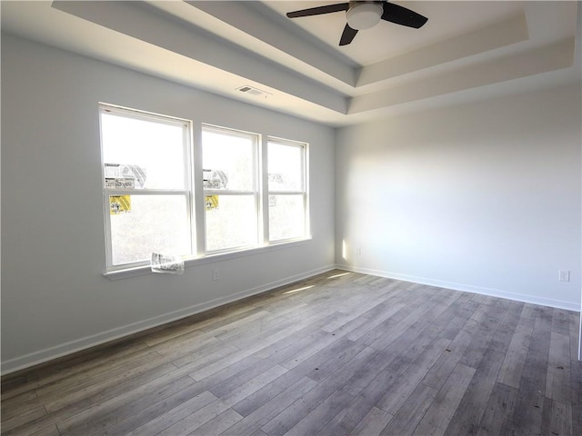 unfurnished room featuring a tray ceiling, wood-type flooring, and ceiling fan