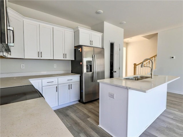 kitchen featuring sink, white cabinetry, stainless steel fridge with ice dispenser, a center island with sink, and hardwood / wood-style floors