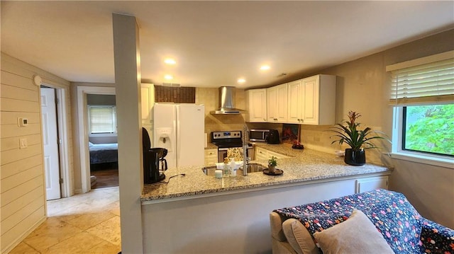 1171 Goodwin Rd NE, Atlanta, GA 30324 - kitchen with wall chimney exhaust hood, appliances with stainless steel finishes, light stone countertops, a peninsula, and white cabinets
