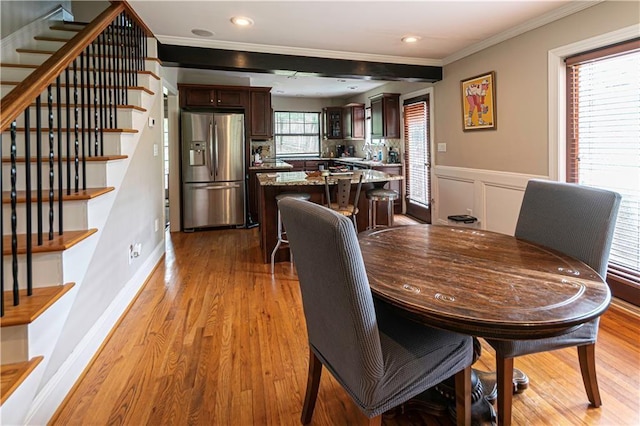 1171 Goodwin Rd NE, Atlanta, GA 30324 - dining space with ornamental molding, stairs, a wainscoted wall, light wood finished floors, and a decorative wall