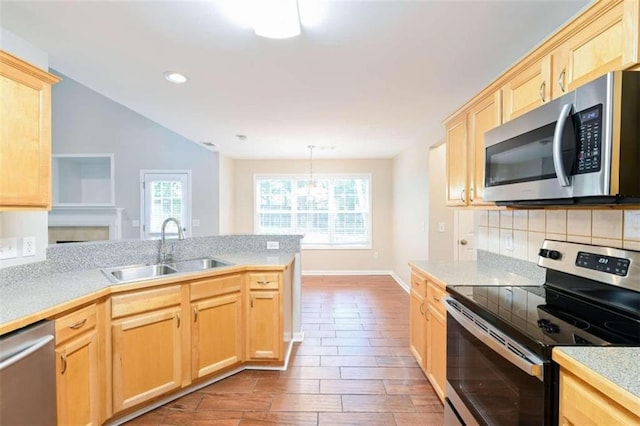 kitchen with appliances with stainless steel finishes, sink, a chandelier, and light brown cabinetry