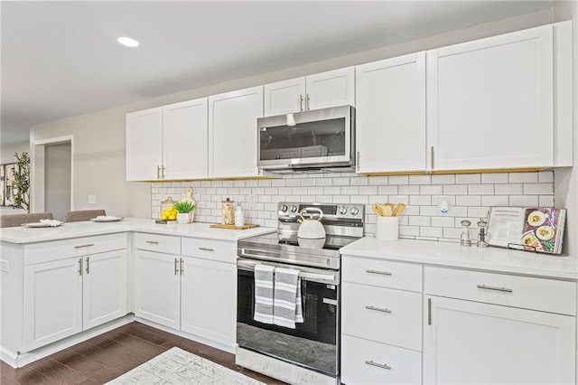 1995 Venetian Dr SW, Atlanta, GA 30311 - kitchen with appliances with stainless steel finishes, a peninsula, light countertops, white cabinetry, and dark wood finished floors