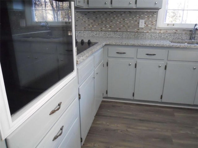 kitchen with white cabinetry, sink, light stone countertops, dark hardwood / wood-style flooring, and decorative backsplash