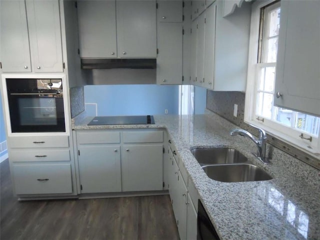 kitchen with light stone counters, dark wood-type flooring, sink, black appliances, and white cabinetry