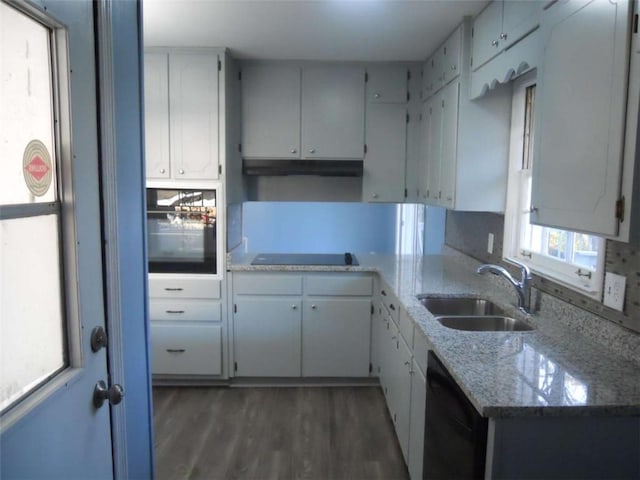 kitchen with dark hardwood / wood-style flooring, light stone counters, black appliances, sink, and white cabinets