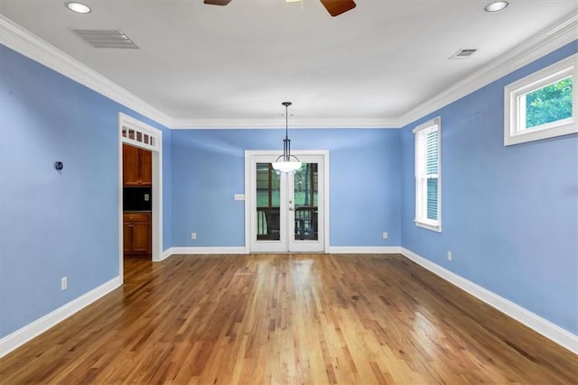 empty room featuring crown molding, wood-type flooring, and a wealth of natural light