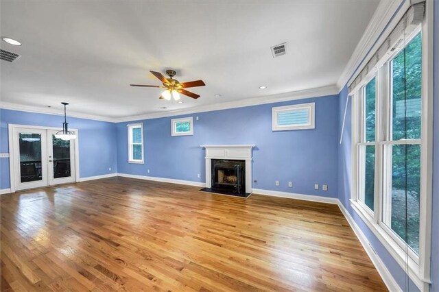 unfurnished living room featuring crown molding, ceiling fan, light wood-type flooring, and a wealth of natural light