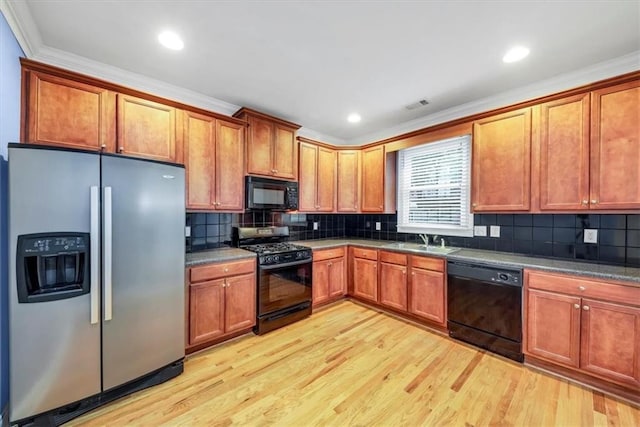 kitchen featuring black appliances, sink, light wood-type flooring, crown molding, and decorative backsplash