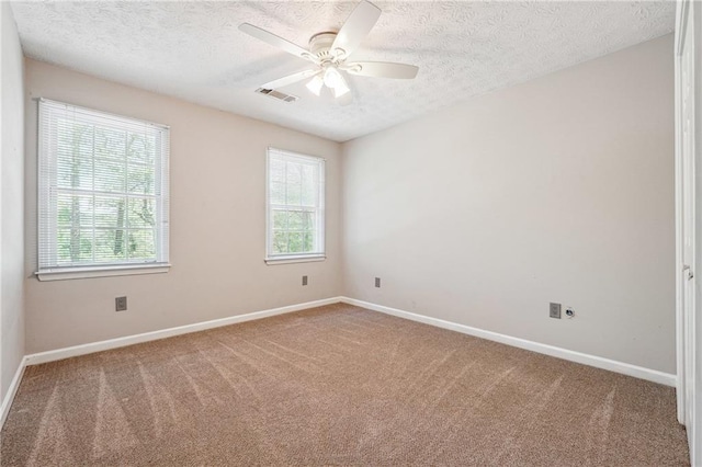 carpeted spare room featuring a ceiling fan, a textured ceiling, visible vents, and baseboards