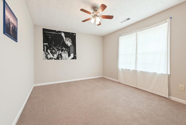 carpeted spare room with visible vents, a ceiling fan, and baseboards