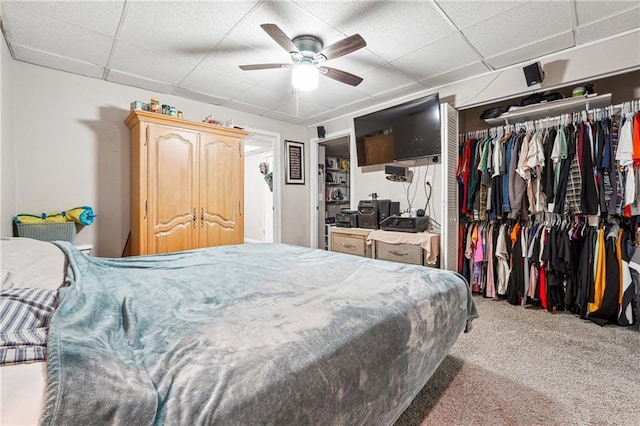 carpeted bedroom featuring a closet, ceiling fan, and a drop ceiling