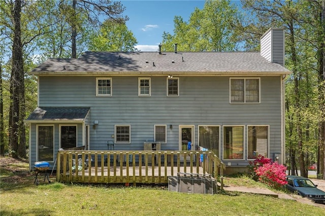 rear view of house featuring a lawn, a wooden deck, and a chimney