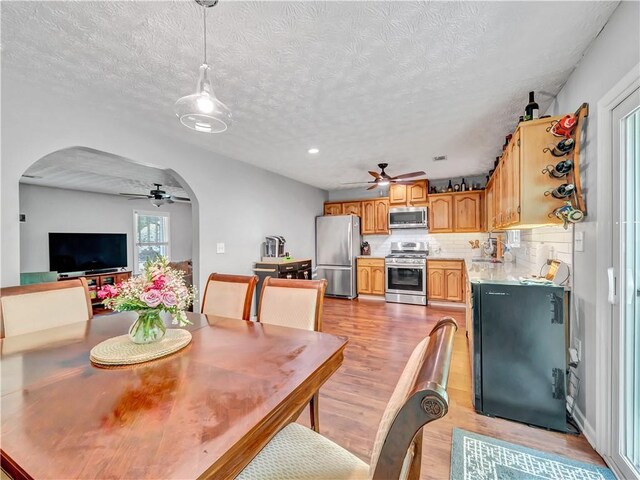 555 Creekwood Xing, Roswell, GA 30076 - dining space featuring a ceiling fan, arched walkways, a textured ceiling, and light wood-type flooring