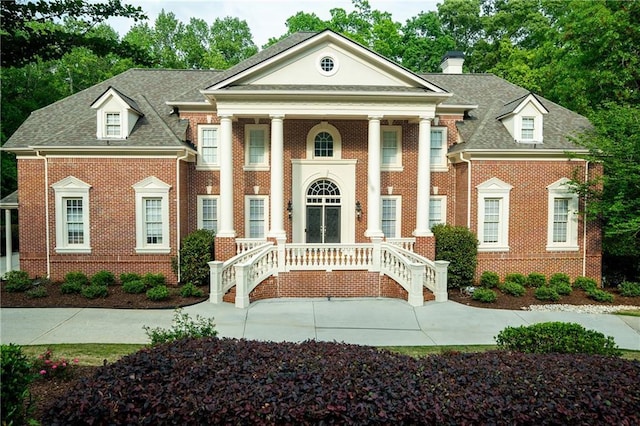 view of front of house featuring a chimney, brick siding, and roof with shingles