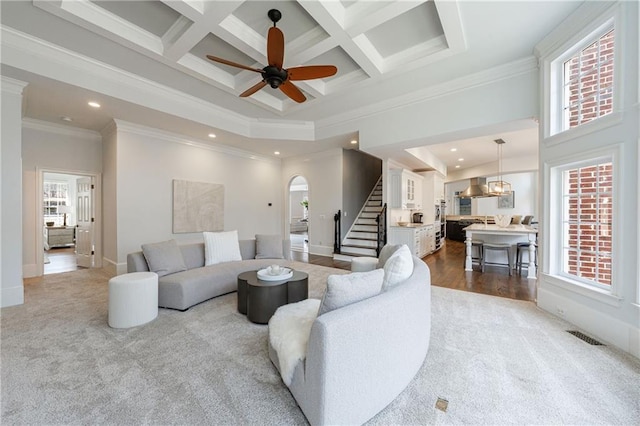 living room featuring recessed lighting, arched walkways, stairs, carpet flooring, and a high ceiling