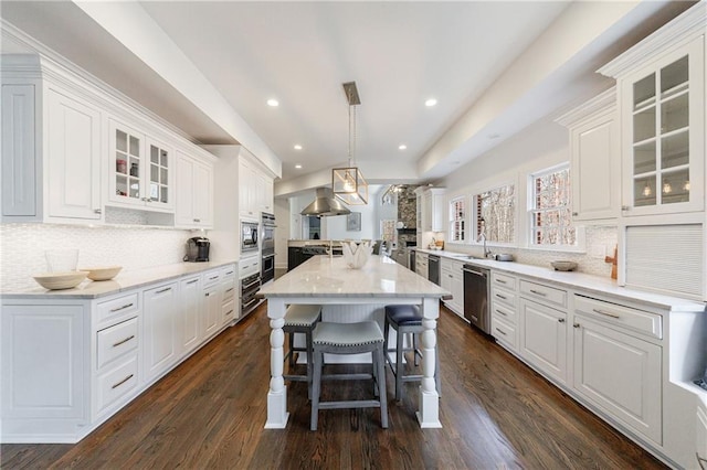 kitchen with backsplash, dishwasher, white cabinetry, glass insert cabinets, and a breakfast bar area