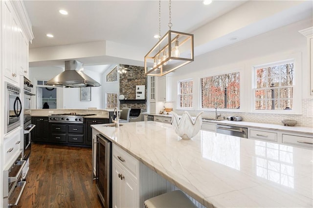 kitchen featuring stainless steel appliances, extractor fan, white cabinetry, decorative backsplash, and beverage cooler