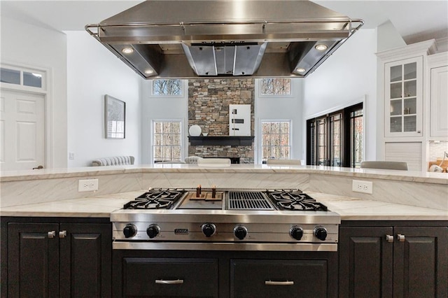 kitchen featuring light stone counters, stainless steel gas cooktop, open floor plan, a wealth of natural light, and exhaust hood