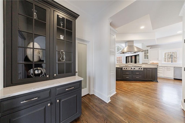 bar with ventilation hood, baseboards, stainless steel appliances, and wood finished floors