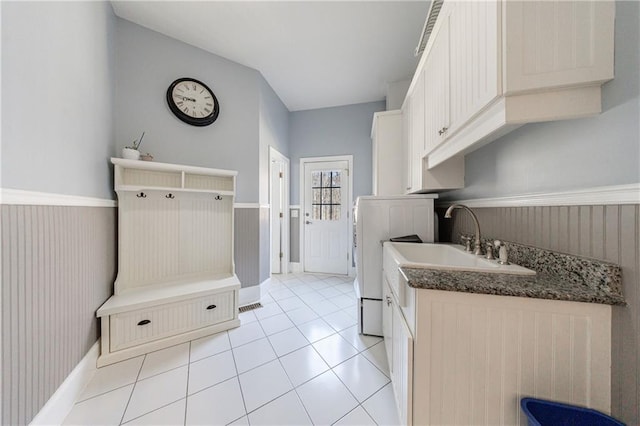 mudroom with baseboards, light tile patterned floors, a wainscoted wall, and a sink